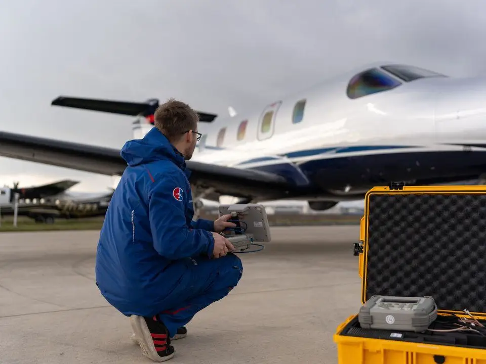 Technician with a test set beside a turboprop on the apron