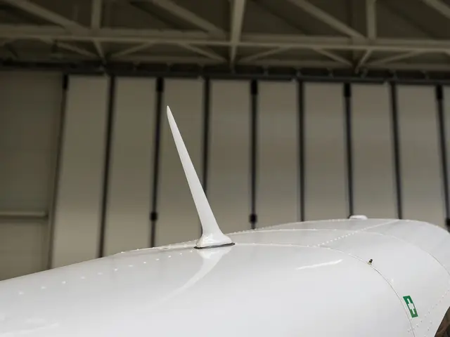 Blade antenna on the fuselage of a white aircraft in a hangar