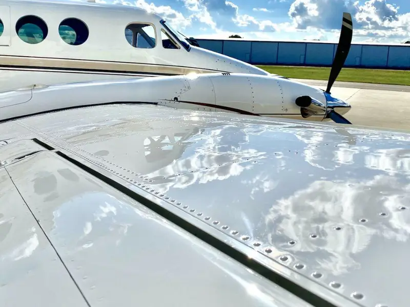 Aircraft wing surface with coating product applied and reflections of clouds