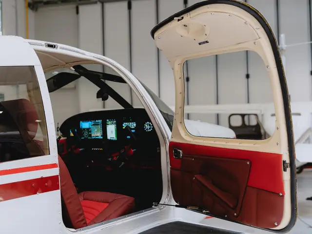 Open door of a Piper Cherokee showing red leather seats and door panel