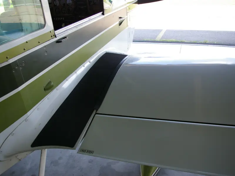 Wing root of a light aircraft with olive and black livery stripes
