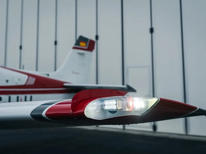 Red and white tail livery and wingtip of a light aircraft in a hangar