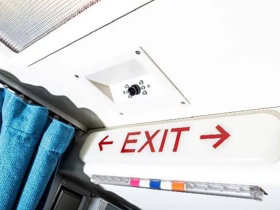 Exit sign above a blue curtain next to a cabin panel