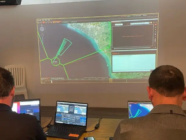 Operators at the GOSHAWK ground station following the live mission map on a projection screen