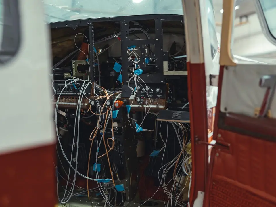 Instrument panel removed with avionics wiring exposed through the open cabin door