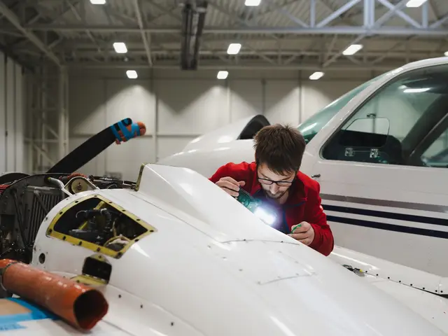 Technician inspecting the nose of a light twin with a torch in the hangar
