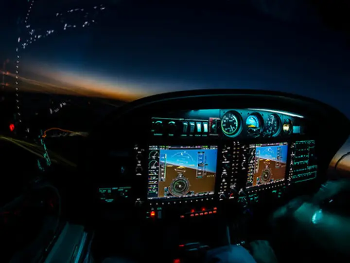 Cockpit at dusk with a lit panel and glass displays