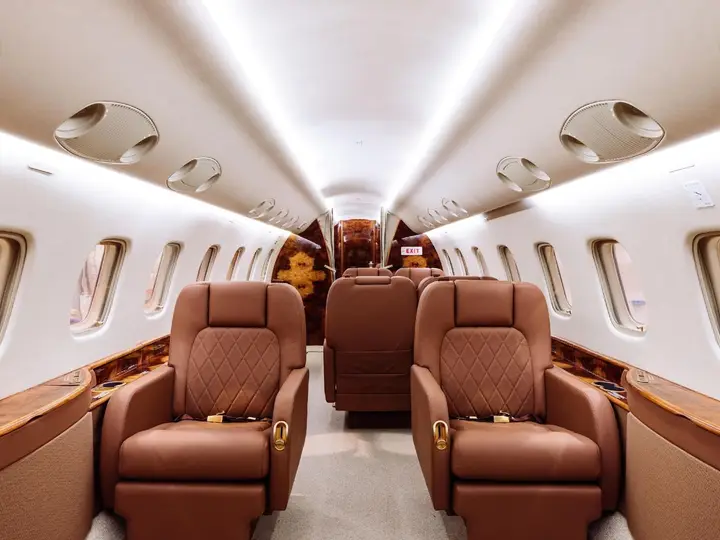 Business jet cabin with club seats, wood trim and cabin lighting